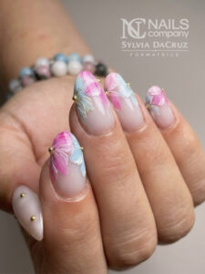 Nail art floral pastel rose et bleu avec micro-billes dorées sur base laiteuse par Sylvia Da Cruz à Sancé.