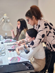 Sylvia Da Cruz guidant une élève pendant une formation de prothésiste ongulaire.